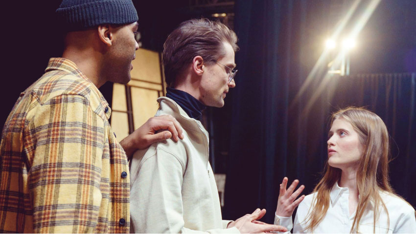 drei junge schauspieler unterhalten sich bei probe auf buehne gross