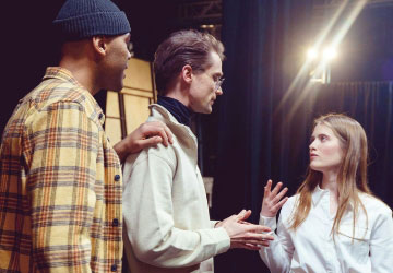 drei junge schauspieler unterhalten sich bei probe auf buehne klein